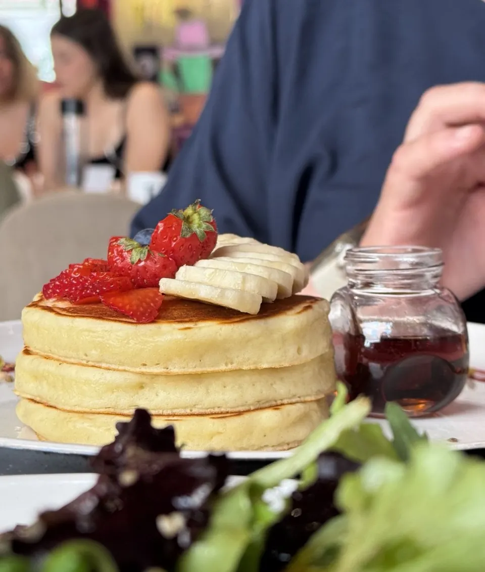 Pancakes soffici con fragole, banana e sciroppo d’acero al tavolo
