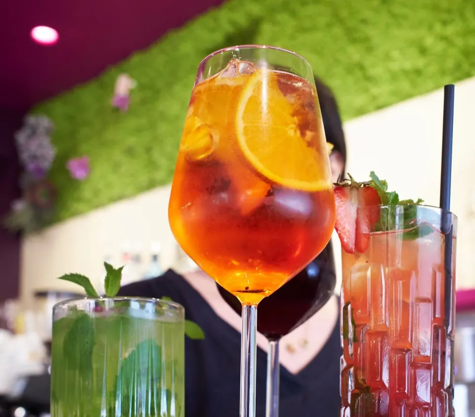 Spritz all’arancia, mojito, sangria e cocktail alla fragola portati al tavolo su un vassoio