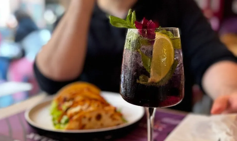 Pranzo al tavolo vicino alla vetrina: tacos e un cocktail ai frutti di bosco